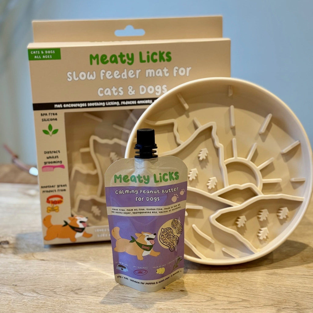 Meaty Licks slow feeder mat for cats and dogs with packaging and product on a wooden surface.