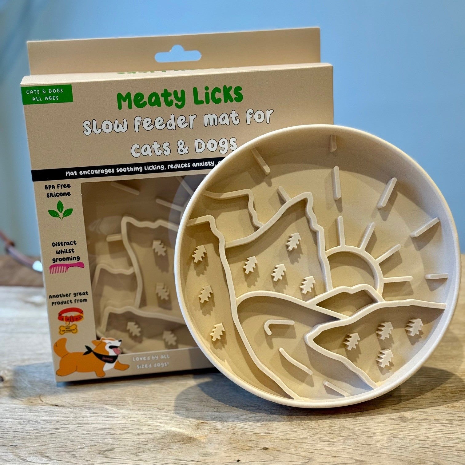 Meaty Licks slow feeder mat for cats and dogs with packaging on a wooden surface.