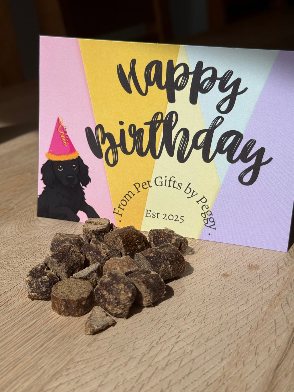 Birthday card with colorful design and text, placed on a textured surface with treats beside it.