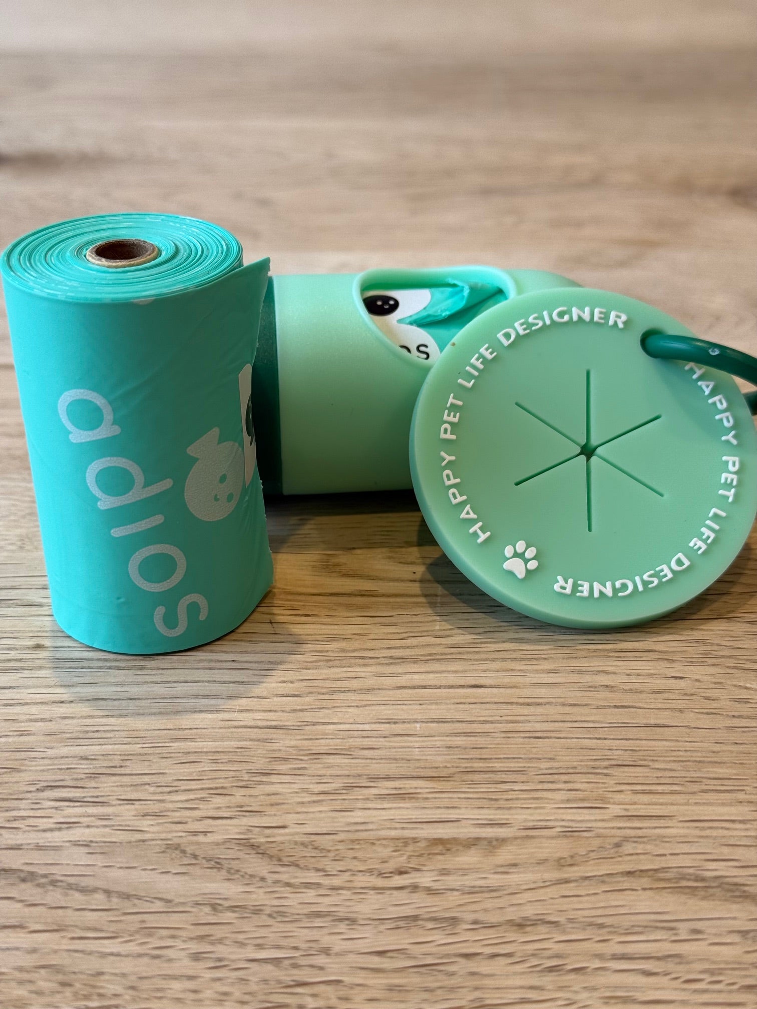 Green pet waste bags with a dispenser on a wooden surface
