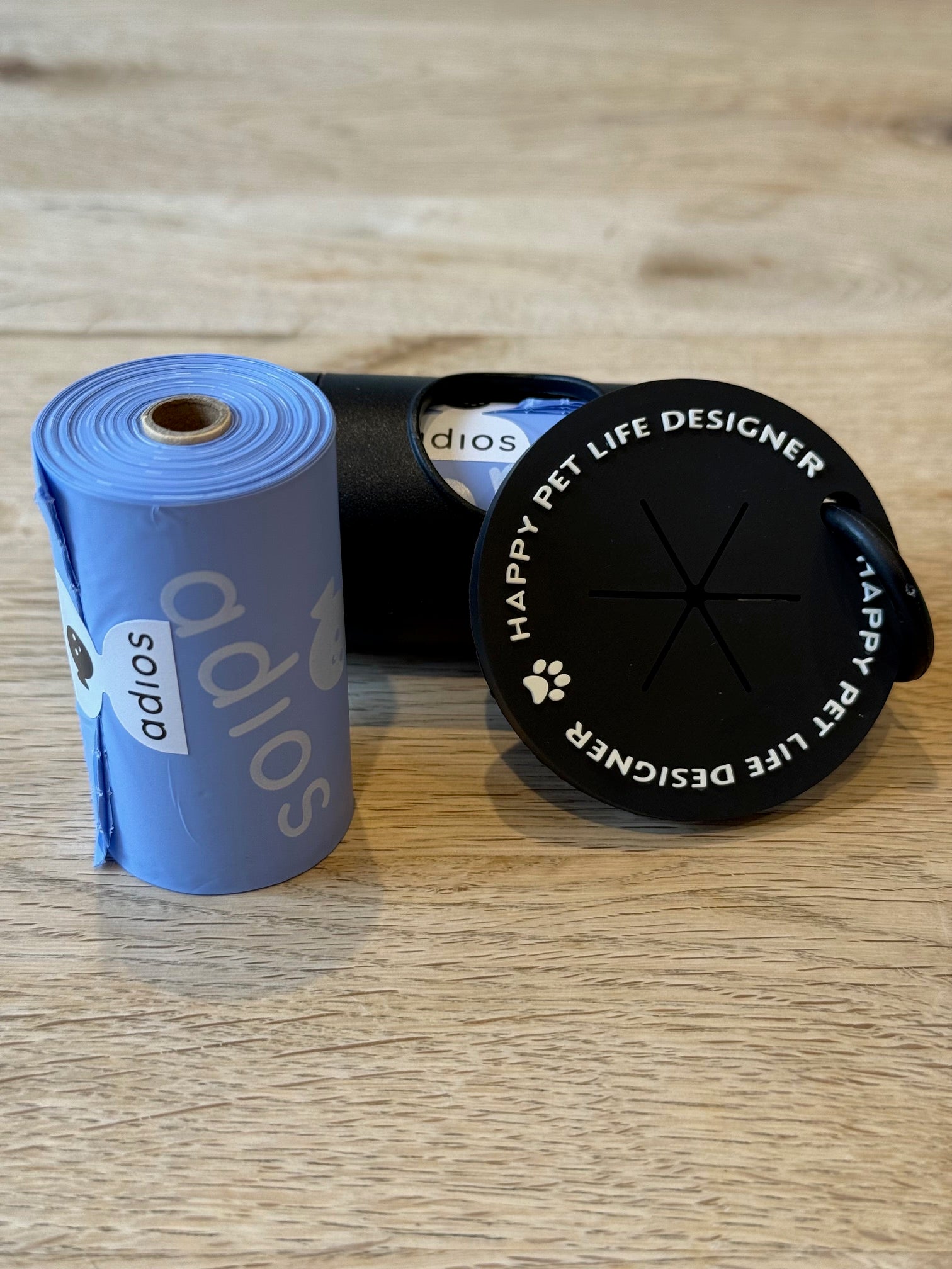 Two rolls of tape, one blue and one black, with 'Happy Pet Life Designer' branding on a wooden surface.