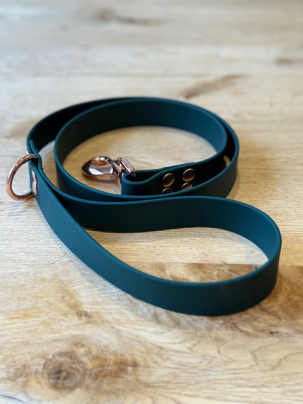 Teal dog leash with rose gold clasp on a wooden surface