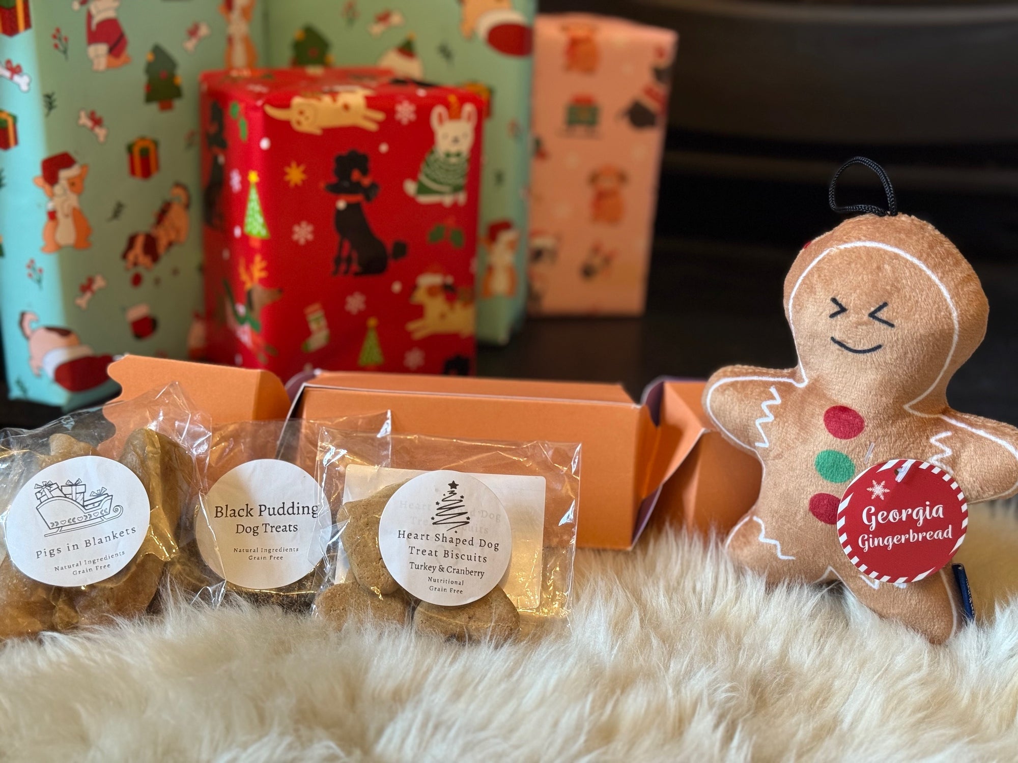 Dog treats in packaging with a gingerbread man ornament on a fluffy surface.