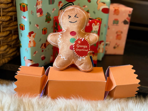 Gingerbread man toy with a name tag on an orange stand against a festive background