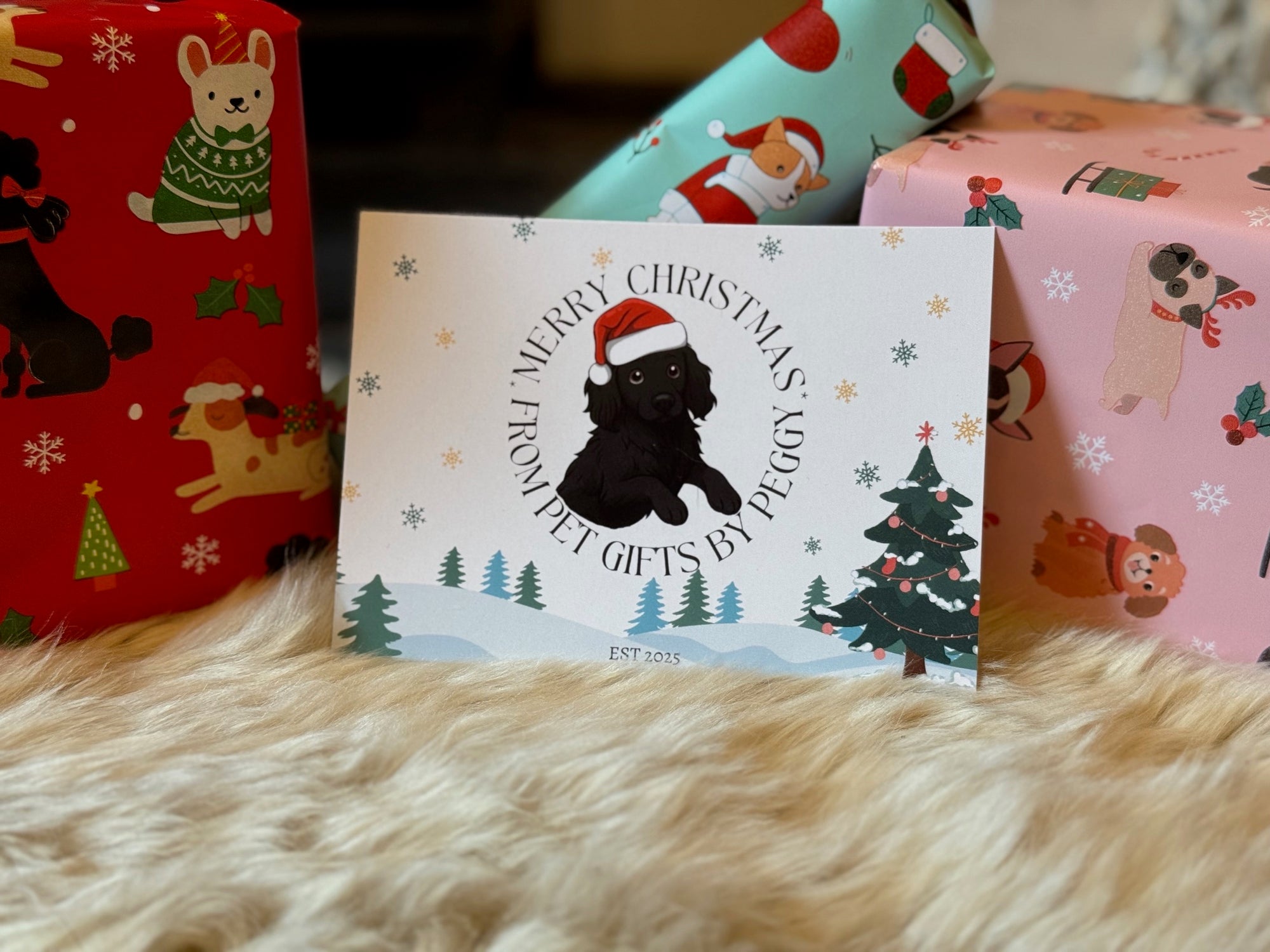 Christmas card with a black dog wearing a Santa hat in front of wrapped presents.
