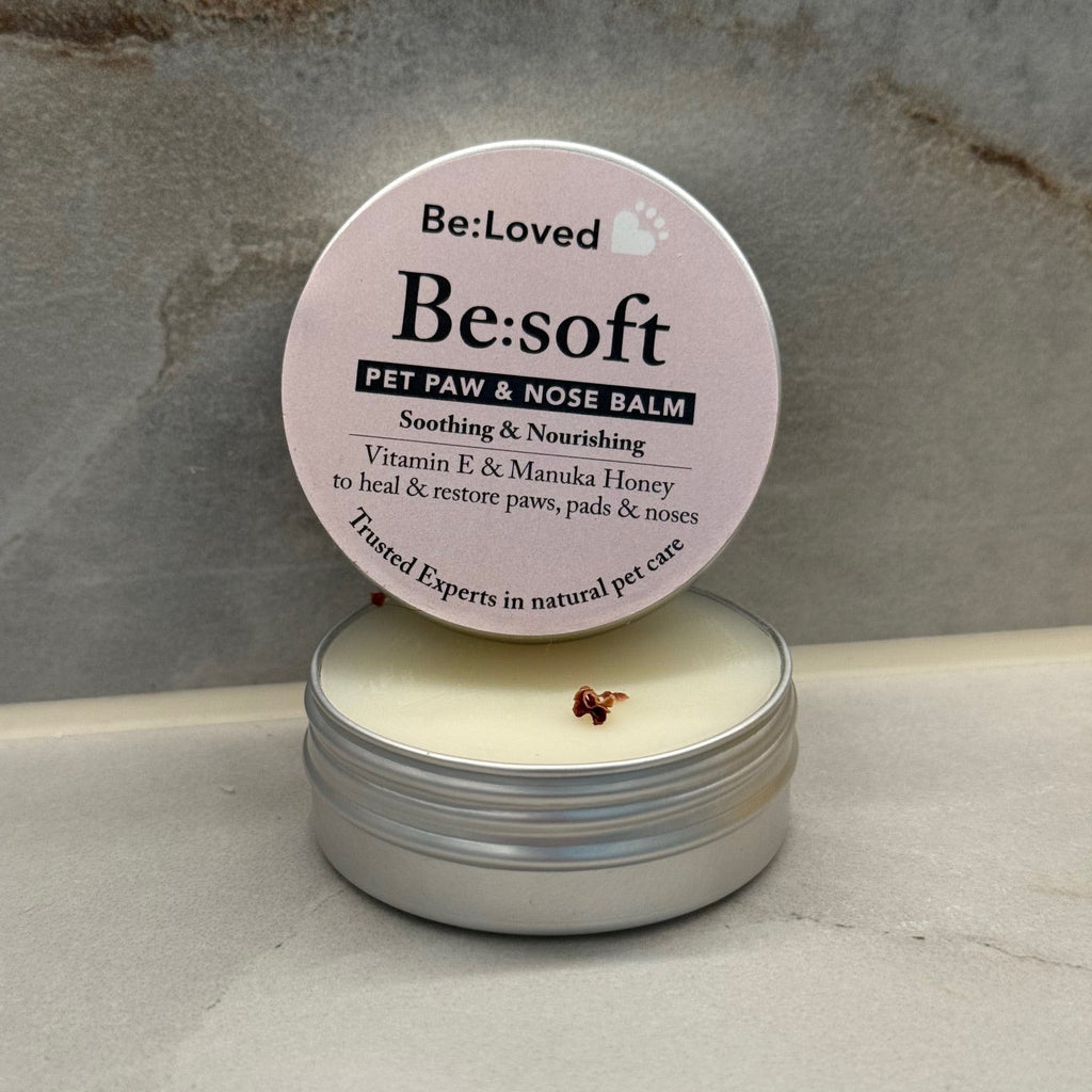 Pet balm container with pink lid on a textured surface