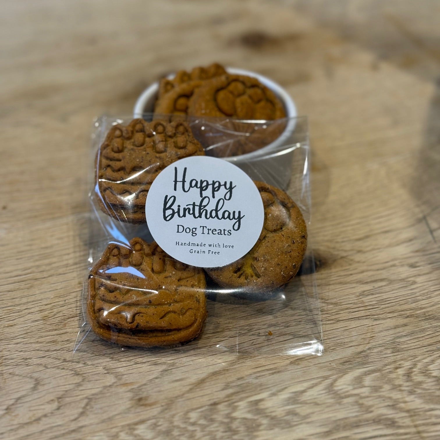 Packaged dog treats with a 'Happy Birthday' label on a wooden surface
