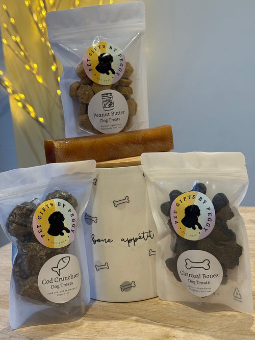 "bone appetit" treat jar with black and gray dog bone print jar surrounded by bags of dog treats 