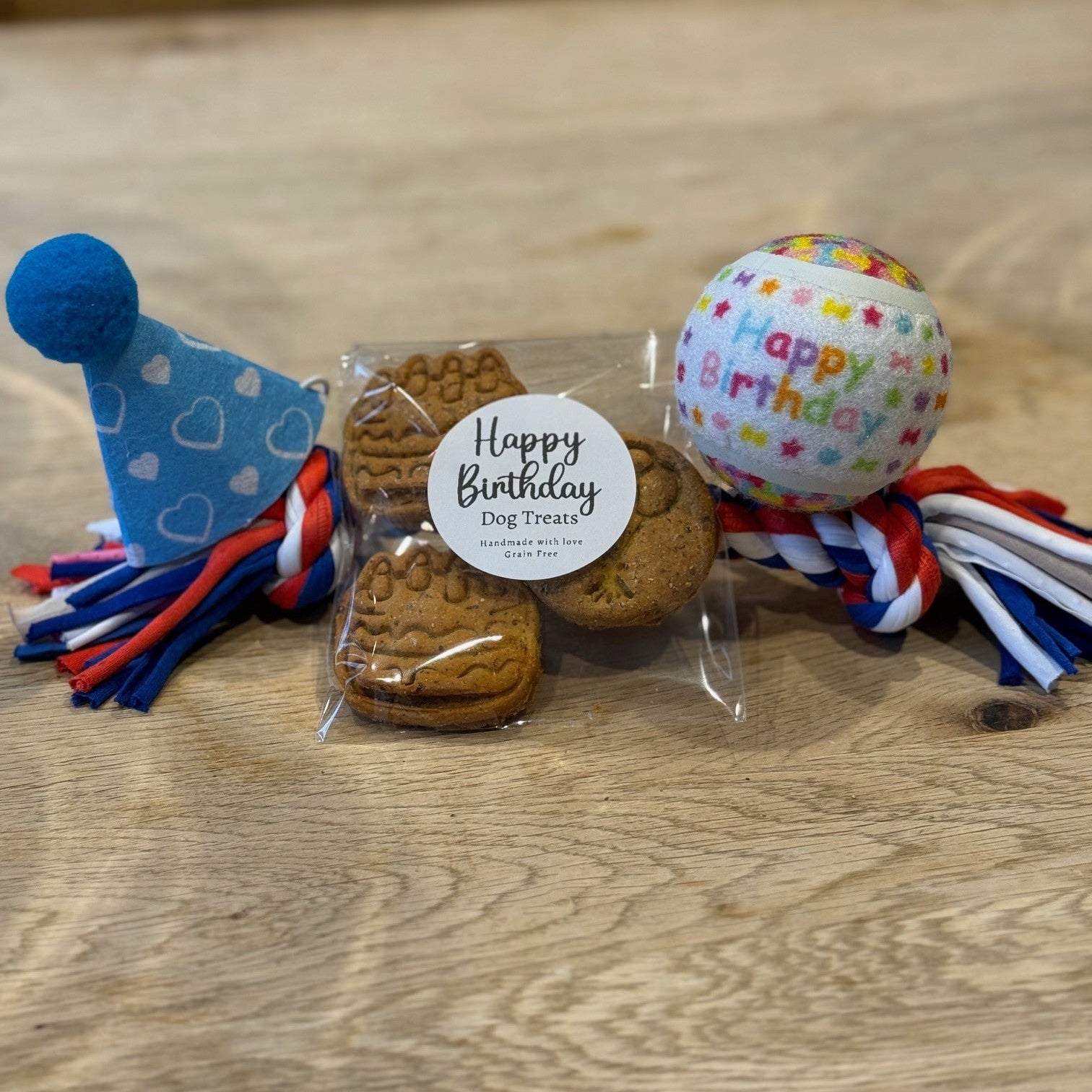 Happy Birthday dog biscuits, happy birthday dog ball, red white and blue dog rope toy and blue dog party hat