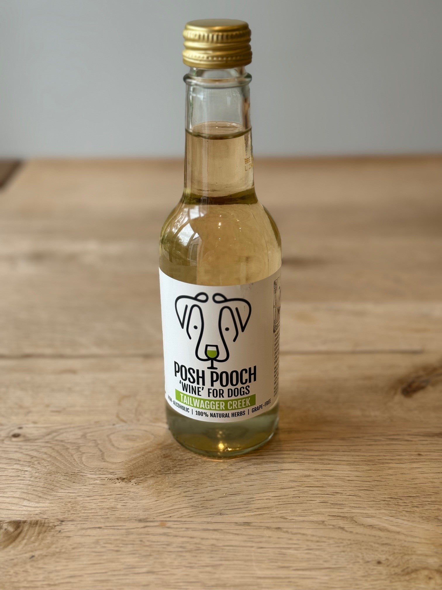 Small bottle of 'Posh Pooch' wine for dogs on a wooden surface
